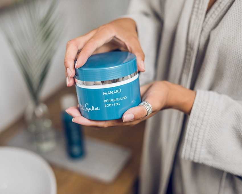 Manaru Körperpeeling in Hand von Frau im Badezimmer