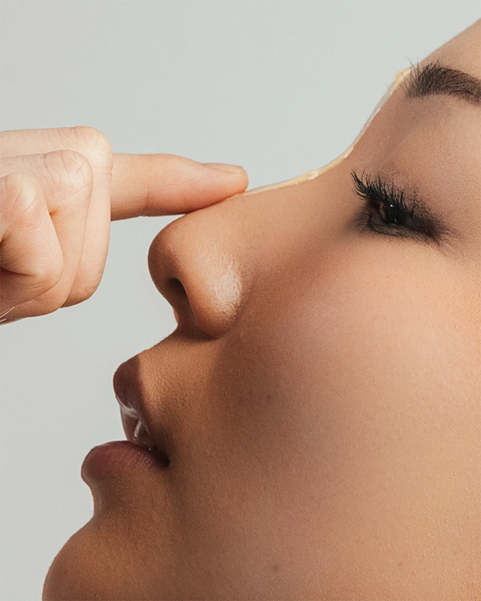 Applying a beige cream on the nose side profile