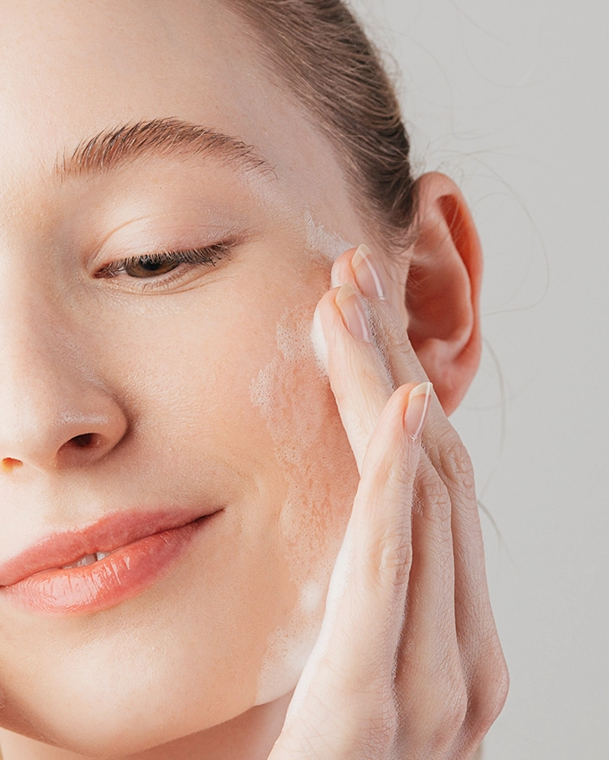 Cleansing foam is emulsified onto the woman's cheek