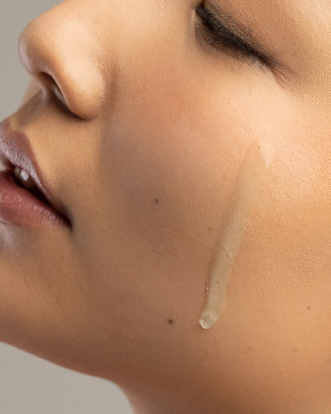 Dünnflüssiges Serum fließt auf Wange von Frau aufgetragen