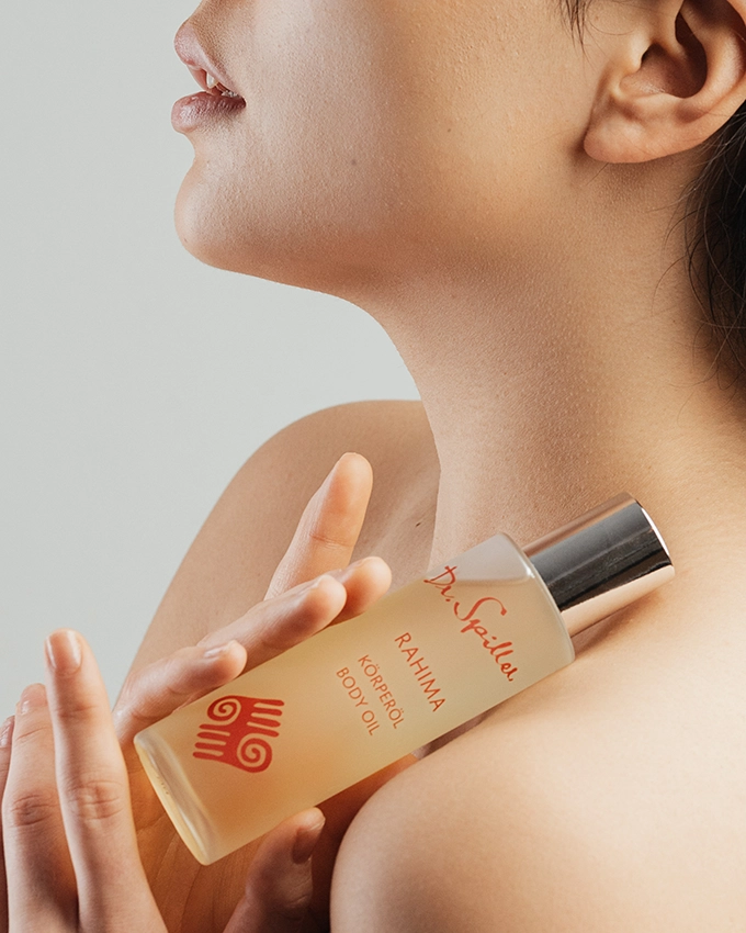 Rahima Körperöl wird vor Schulter von Frau gehalten