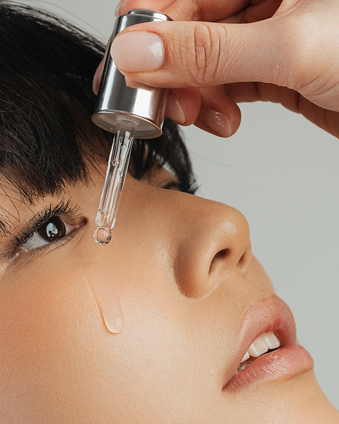 Serum wird mit Pipette auf Wange von Frau aufgetragen