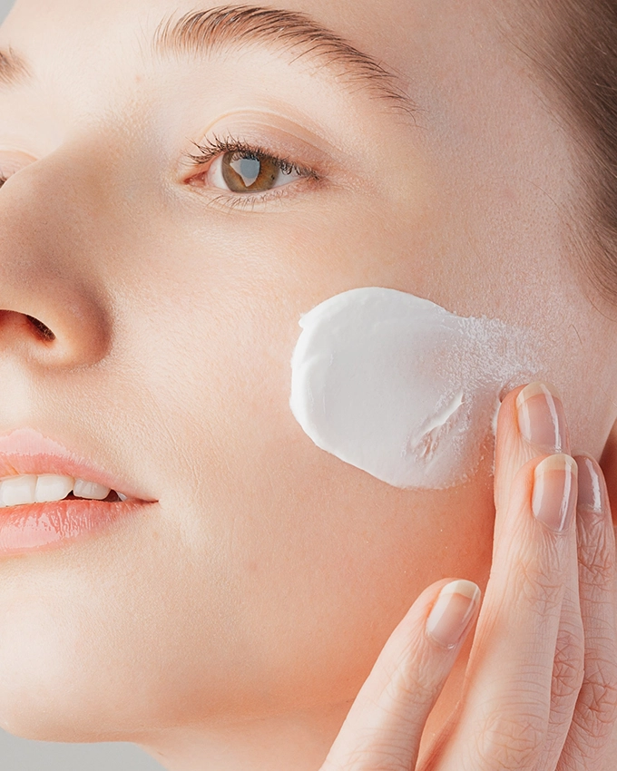 Jojoba peeling cream on woman's cheek