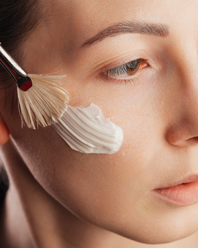 Frau trägt BIO Gesichtscreme mit Pinsel auf ihr Gesicht aus