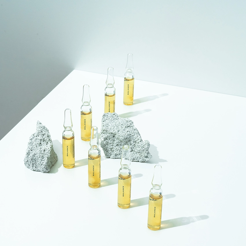 Mehrere Ampullen stehen auf einem Tisch mit Dekosteinen