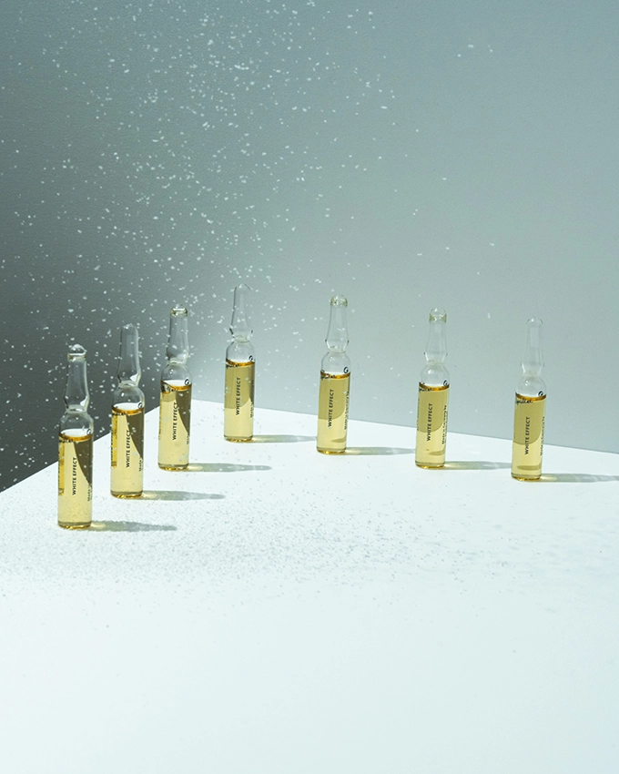 Several ampoules stand on a table with a bluish background with beads of water from above