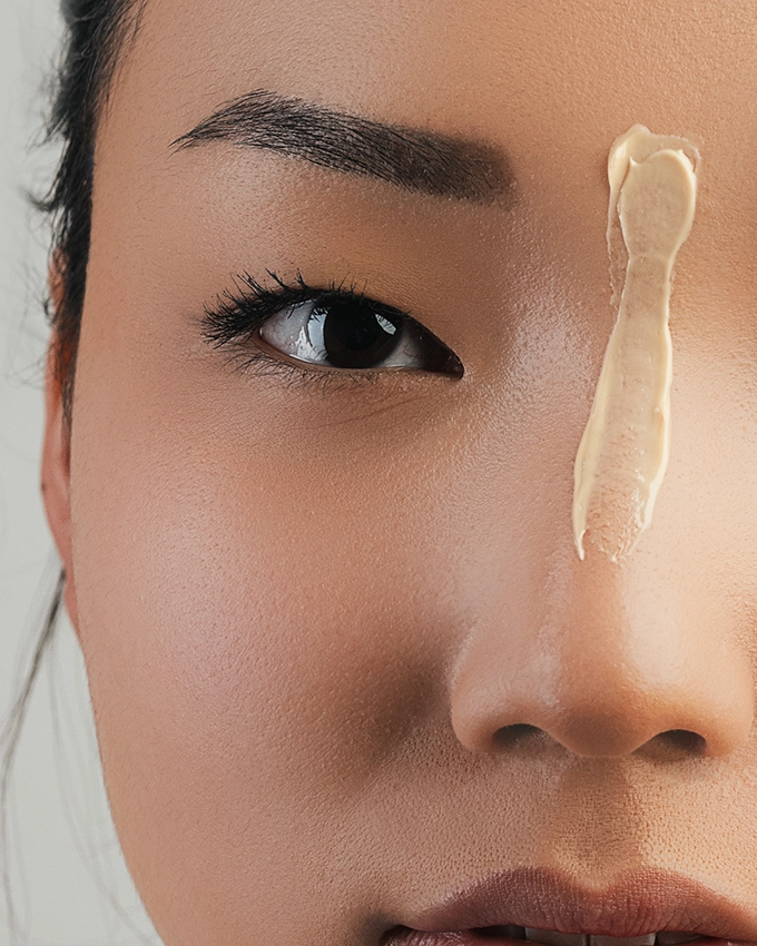 Applying a beige-colored cream to the nose from the front