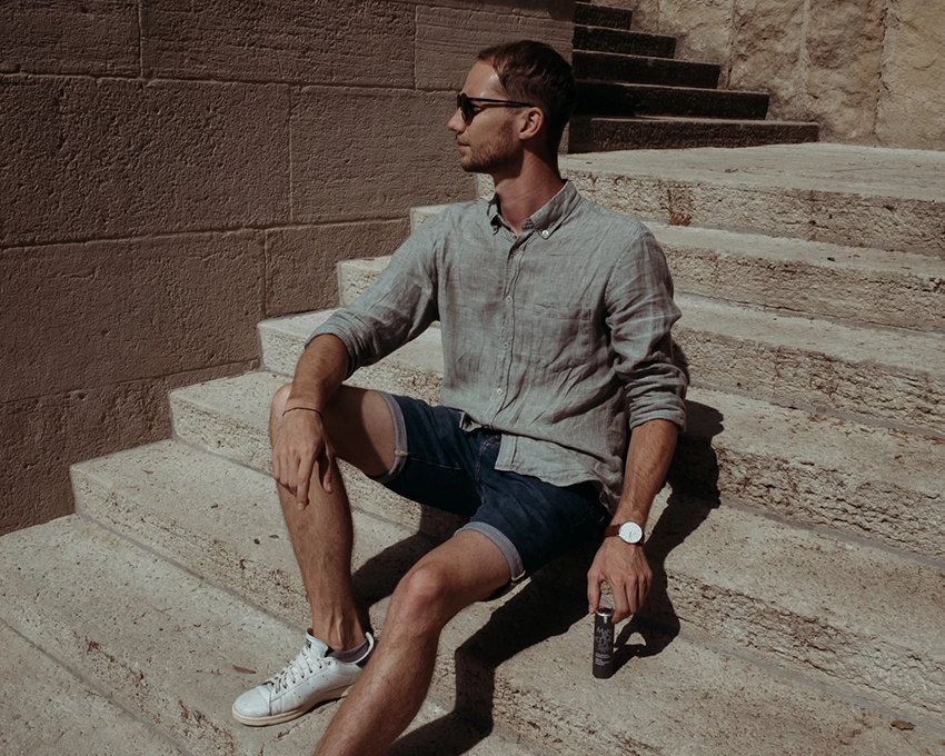 Mann posiert auf einer Treppe mit MYs Pflegeprodukt in der Hand