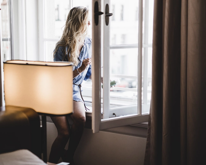 Woman looking out of the window of a stylishly furnished apartment