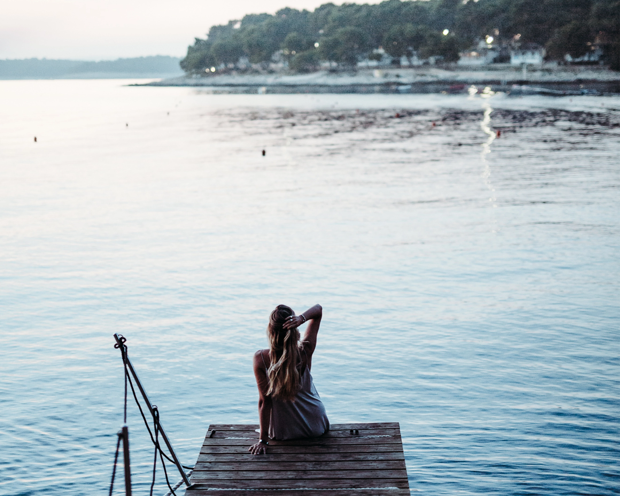 Woman sitting on the jetty overlooking the sea