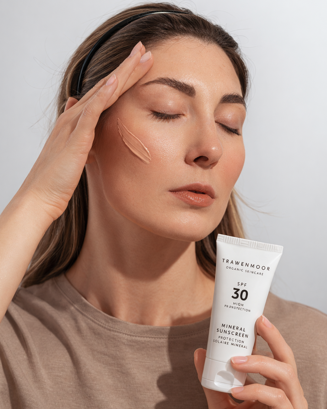 A woman applies cream to her face