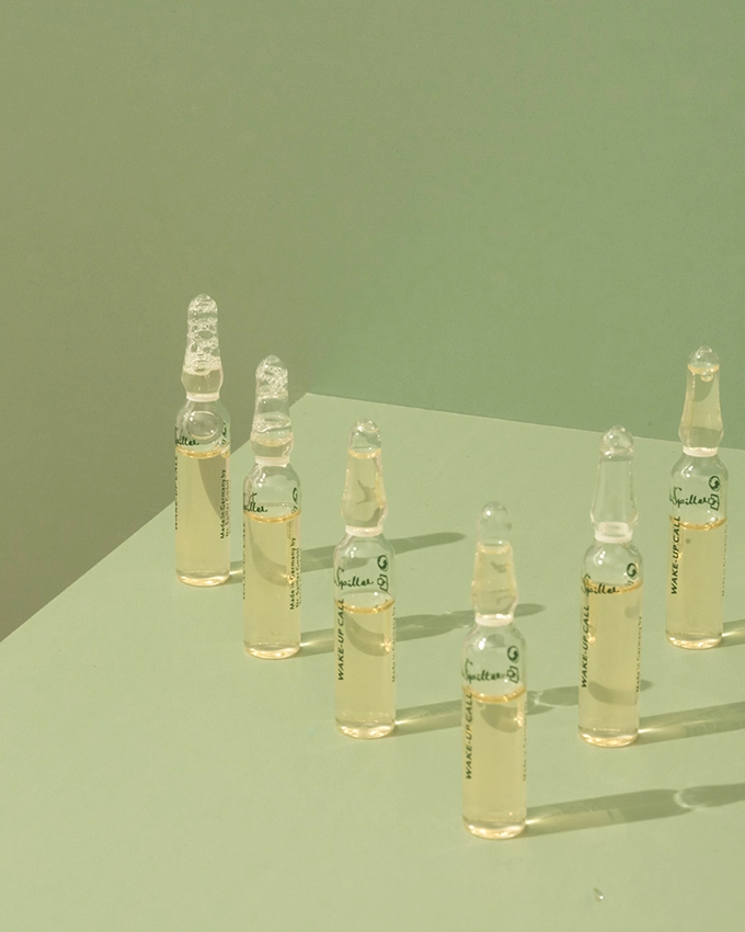 Several ampoules are placed on a table with a green background