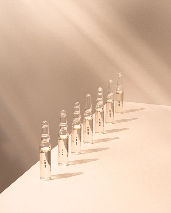 Mehrere Ampullen stehen auf einem Tisch mit rosafarbenen Hintergrund