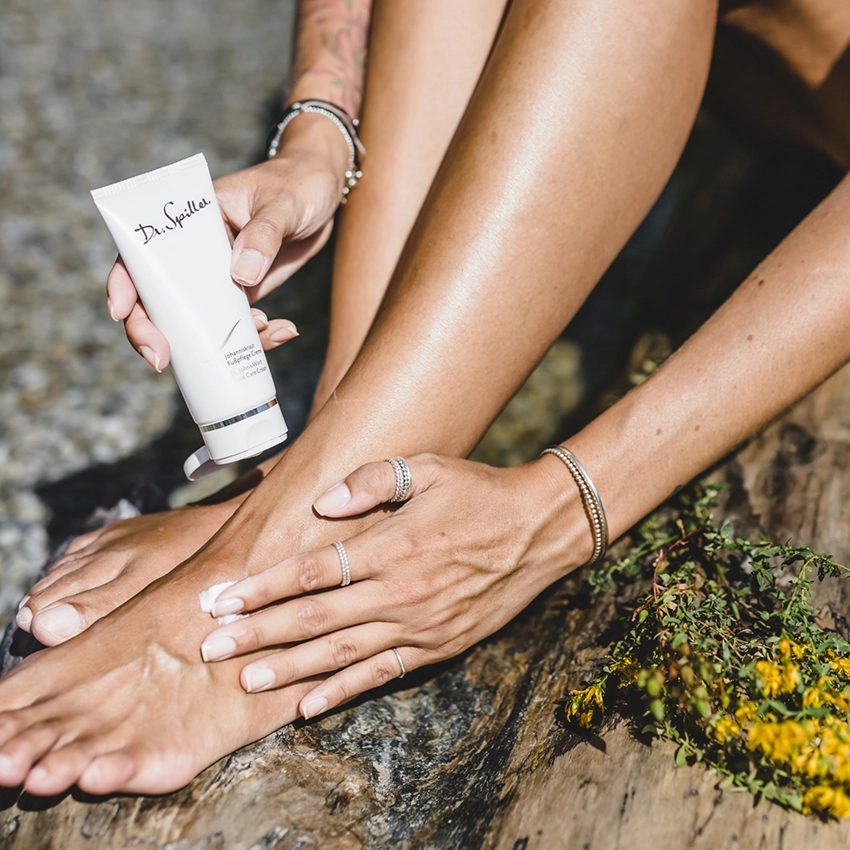 Fußpflegeprodukt neben Beinen mit glatter Haut