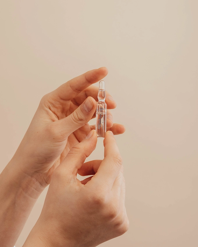 Woman holding a face ampoule with two hands